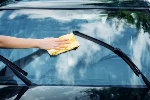 Mano femenina con ventana de lavado de esponja amarilla del coche — Foto de Stock