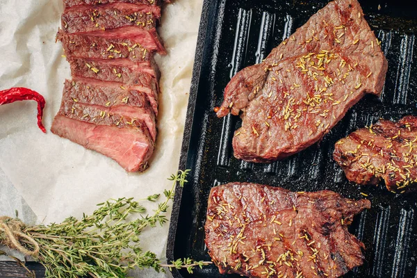 Bistecca di manzo alla griglia sulla padella, vista dall'alto. Pezzi di carne fritti da vicino — Foto Stock