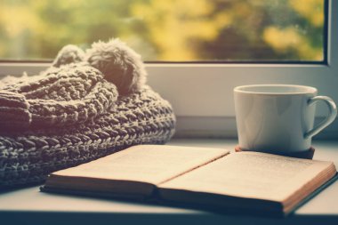 Yün, ipek eşarp, bir fincan çay ve Pencere pervazı kitap. Hygge ve rahat sonbahar konsepti