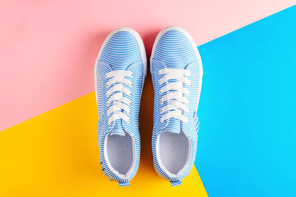 Blue striped female sneakers on a colorful background top view. Flat lay minimal background