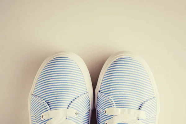 Primo piano di scarpe da ginnastica femminili a strisce blu su uno sfondo bianco vista dall'alto. Flat lay sfondo minimo, foto tonica — Foto Stock