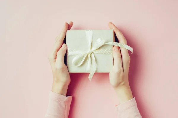 Mani della donna che tengono scatola regalo su sfondo rosa, vista dall'alto — Foto Stock