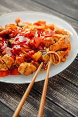 Udon noodle tavuk ve sebze beyaz bir plaka ile yakın çekim