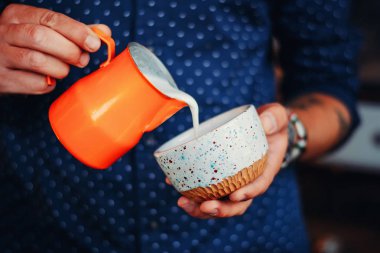 adam süt fron sürahiye kahve Kupası, cappuccino veya latte, yakın çekim yapma barista eller