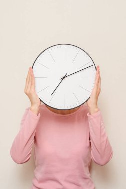 Bir saat yüzünü kaplayan kız. Kadın stres ve son tarih konseptinden gizler