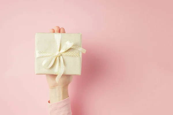 Donna mano tiene scatola regalo su palmo su sfondo rosa con spazio copia — Foto Stock
