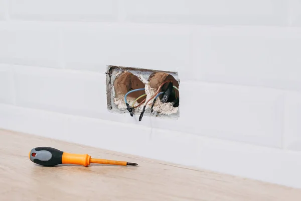 place for installation of power socket with protruding wires and screwdriver. Installation of power socket