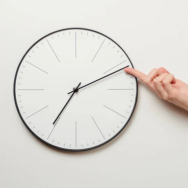 Mulher mão tempo de parada no relógio redondo, dedo feminino leva a seta minuto do relógio de volta, gerenciamento de tempo e conceito de prazo — Fotografia de Stock