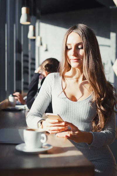 Mooie meisje in café maakt gebruik van een smartphone — Stockfoto