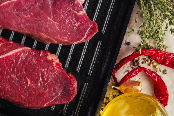 Fette di carne cruda fresche su padella vista dall'alto. Bistecche di manzo pronte per la cottura con olio d'oliva e spezie — Foto Stock