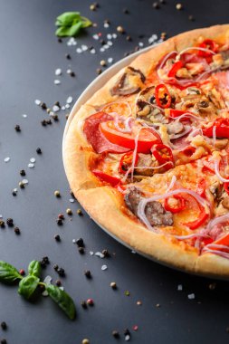 İtalyan pizza ve taze fesleğen yaprakları koyu bir kağıt üzerinde yarısı kadar yakın. Geleneksel İtalyan mutfağı