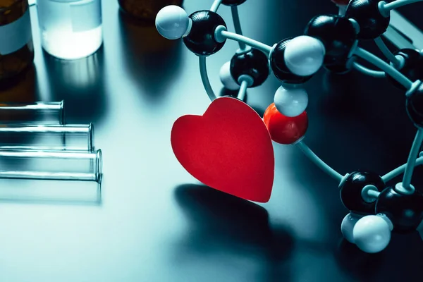 Rotes Papierherz und Molekularstrukturmodell auf schwarzem Hintergrund. Liebe Chemie Konzept — Stockfoto