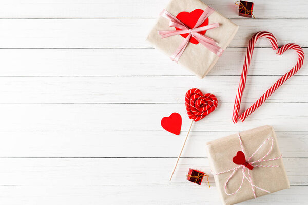 Concept of Valentines Day. Heart shaped candy and gift boxes on a white wooden background with copy space, top view