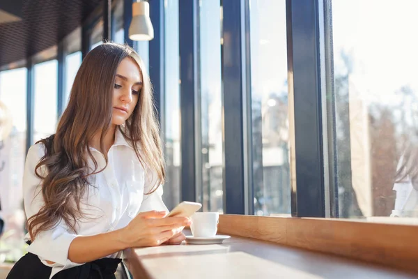 Mooie jongedame in zakelijke kleding smartphone gebruiken in een café — Stockfoto