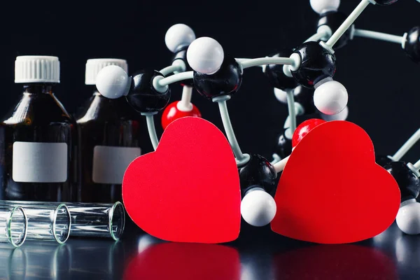 Dois corações de papel vermelho e modelo de estrutura molecular num fundo preto. Conceito de química do amor — Fotografia de Stock