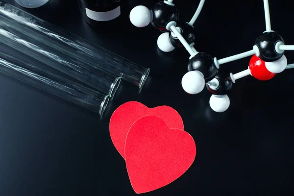 Dois corações de papel vermelho e modelo de estrutura molecular num fundo preto. Conceito de química do amor — Fotografia de Stock