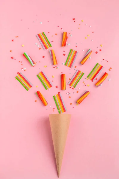 Cuerno de papel con dulces de mermelada de colores sobre un fondo rosa, vista superior, puesta plana. Estilo de moda minimalista — Foto de Stock