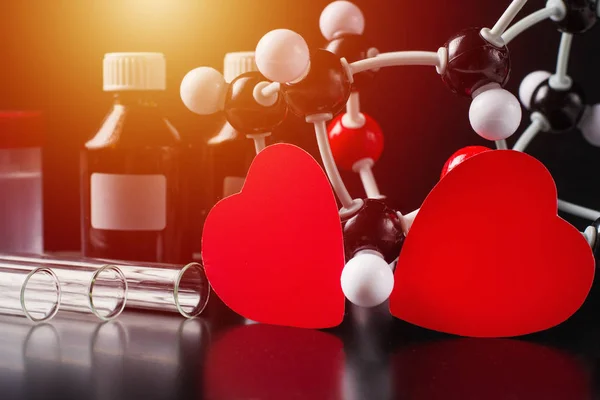 Dois corações de papel vermelho e modelo de estrutura molecular num fundo preto. Conceito de química do amor — Fotografia de Stock