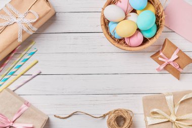 Hediye kutuları, Paskalya yumurtaları ve süslemeleri Beyaz ahşap arka planda, kopya alanı ile üstten görünüm