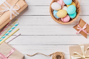 Hediye kutuları, Paskalya yumurtaları ve süslemeleri Beyaz ahşap arka planda, kopya alanı ile üstten görünüm