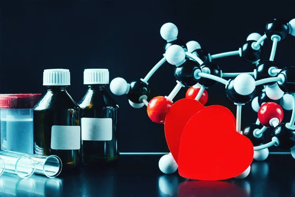 Dois corações de papel vermelho e modelo de estrutura molecular num fundo preto. Conceito de química do amor — Fotografia de Stock