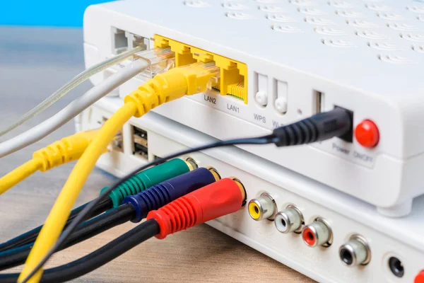 Router nirkabel rumah dengan kabel ethernet terpasang pada latar belakang biru, closeup — Stok Foto