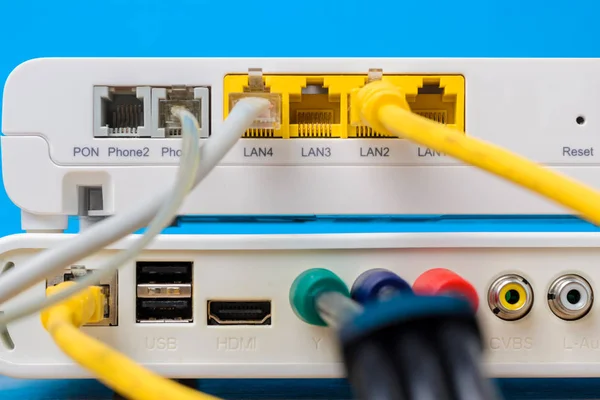 home wireless router with ethernet cables plugged in on blue background, closeup