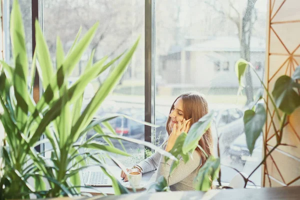 Mooie jonge vrouw praten over mobiele telefoon en lachend in een café — Stockfoto