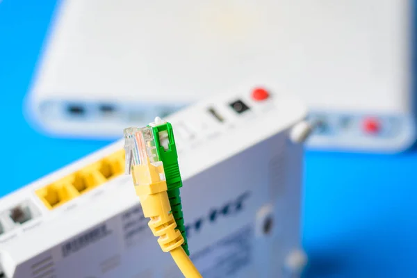 Kabel optik dan jaringan dengan router nirkabel internet pada latar belakang biru — Stok Foto
