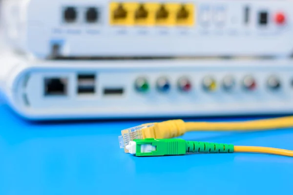 Kabel optik dan jaringan dengan router nirkabel internet pada latar belakang biru — Stok Foto