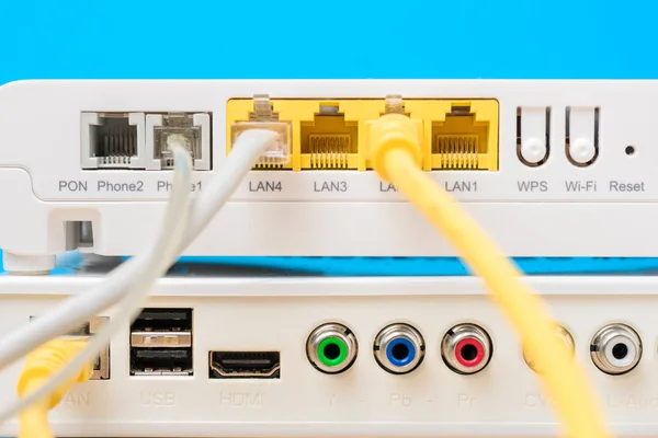Router nirkabel rumah dengan kabel ethernet terpasang pada latar belakang biru, closeup — Stok Foto
