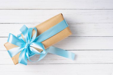 gift box with blue bow on a white wooden background with copy space clipart