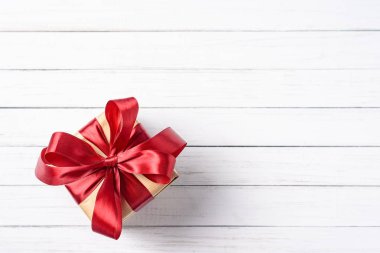 kopya alanı beyaz bir ahşap zemin üzerine kırmızı fiyonklu hediye kutusu