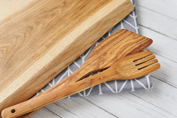 Utensilios de cocina, tabla de cortar, espátula y toalla sobre un fondo de madera blanco — Foto de Stock