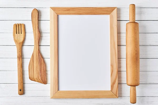 Utensilios de cocina y sábana vacía en un marco de madera sobre fondo blanco. maqueta de cocina — Foto de Stock