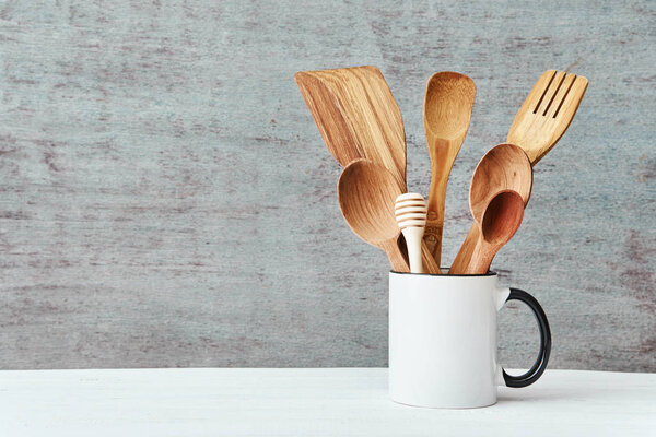 Kitchen utensils in ceramic cup on a gray background, copy space
