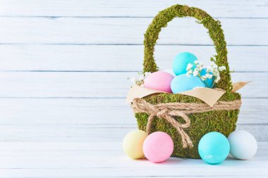 Backet Beyaz ahşap arka plan üzerinde renkli Paskalya yumurtaları