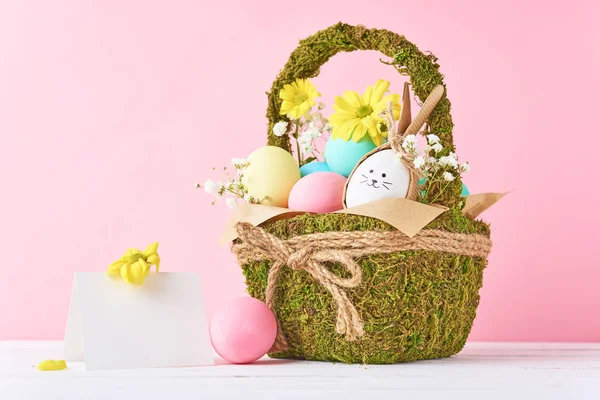 Пасхальная концепция. Пасхальные яйца в декоративной корзине с цветами на розовом фоне — стоковое фото