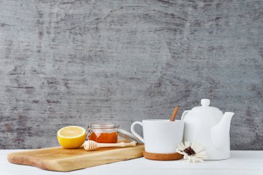 Seramik çaydanlık, beyaz Kupası, cam ve ahşap zemin üzerine limon bal
