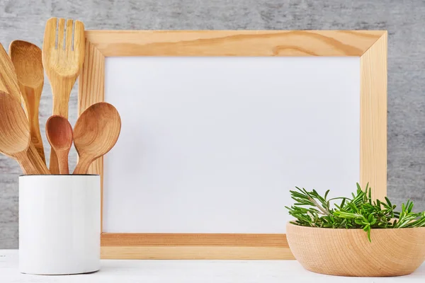 Utensilios de cocina fondo con papel blanco vacío y cubiertos de madera en una taza sobre una mesa blanca, maqueta de cocina — Foto de Stock