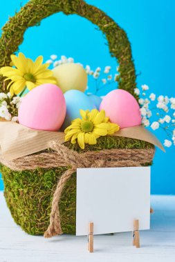 Backet mavi bir arka plan üzerinde renkli Paskalya yumurtaları