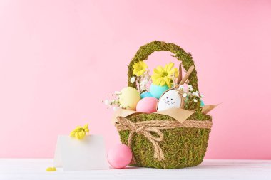 Paskalya kavramı. Çiçekli pembe bir arka plan üzerinde dekoratif sepet içinde Paskalya yumurtaları