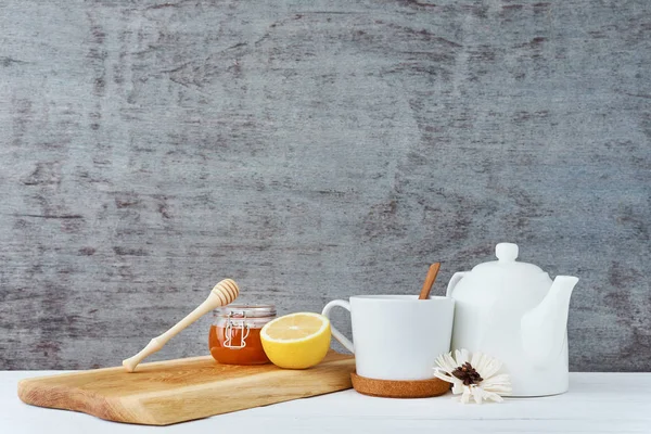 Tetera de cerámica, taza blanca, miel en un frasco de vidrio y limón sobre fondo de madera — Foto de Stock