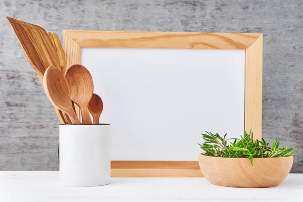 Utensilios de cocina fondo con papel blanco vacío y cubiertos de madera en una taza sobre una mesa blanca, maqueta de cocina — Foto de Stock