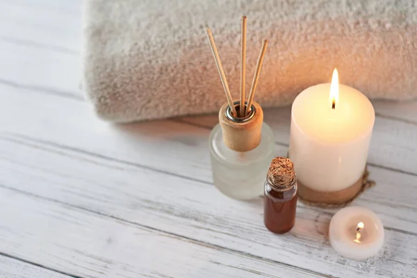 Toallas, velas y aceite de masaje sobre mesa blanca — Foto de Stock