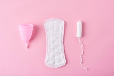 Hijyenik ped, adet kupa ve tampon pembe bir arka plan üzerinde