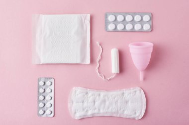 Hijyenik ped, adet Kupası, tampon ve tabletler üzerinde pembe bir arka plan, üstten görünüm