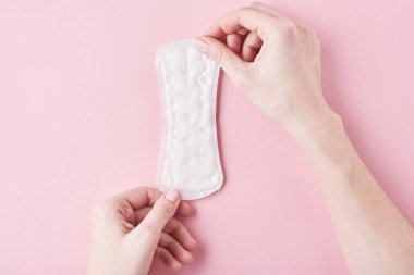 Kadın el hijyenik ped pembe bir arka plan üzerinde tutun.
