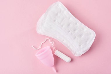 Hijyenik ped, adet kupa ve tampon pembe bir arka plan üzerinde
