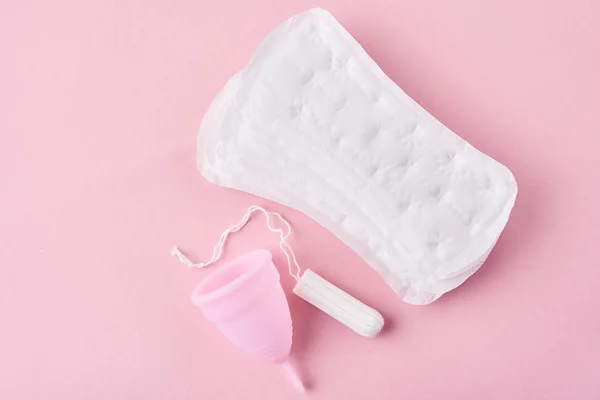 Pad sanitasi, cangkir menstruasi dan tampon pada latar belakang merah muda — Stok Foto